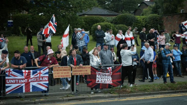 Rival groups face off outside migrant hotel - as asylum seekers 'blow kisses' at protesters
