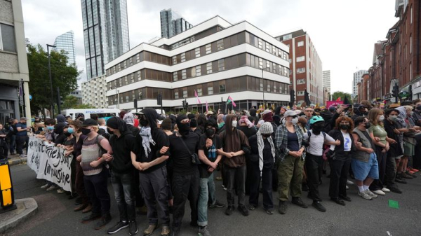 Rival groups face off outside migrant hotel - as asylum seekers 'blow kisses' at protesters