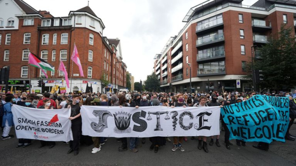 Rival groups face off outside migrant hotel - as asylum seekers 'blow kisses' at protesters